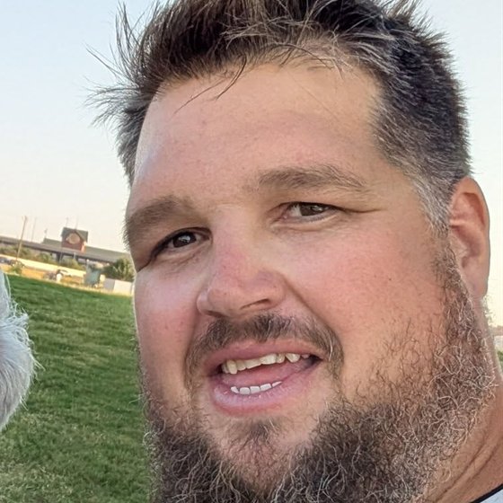 Dusty Stillwell outdoors at golden hour, mid-sentence, smiling.